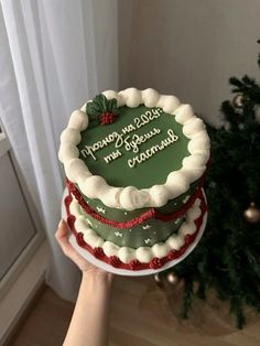 a person holding a christmas cake in front of a tree