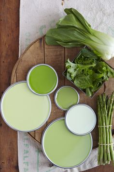 some green paint is sitting on a table next to asparagus and other vegetables