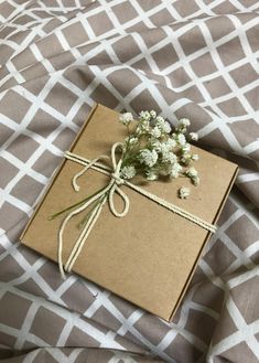 a brown box with some flowers tied to it on a bed sheet that is covered in grey and white fabric