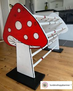 a large red mushroom sitting on top of a wooden floor next to a white railing