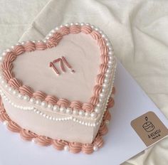 a heart - shaped cake with pearls and pink icing on a white tablecloth