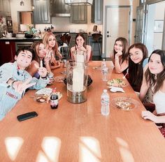 a group of people sitting around a table with food and drinks in front of them