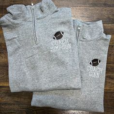 two gray sweatshirts with the words coach simpson and football on them sitting on top of a wooden floor