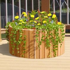 a wooden planter filled with lots of flowers on top of a hard wood deck