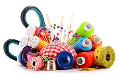 a pile of different colored spools of thread and sewing needles on a white background