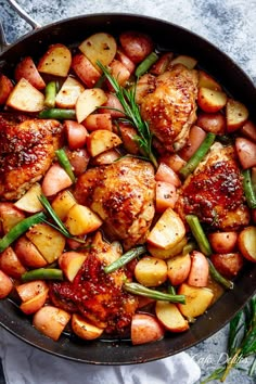 chicken, potatoes and green beans in a skillet with rosemary garnishes