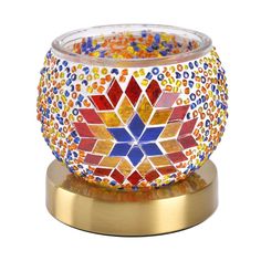 a colorful glass candle holder on a gold plated stand with a circular base and multicolored beads in the center