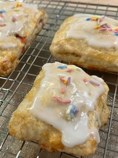 three pastries with icing and sprinkles on a cooling rack