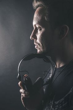 a man holding a pair of headphones in his hand and looking off into the distance