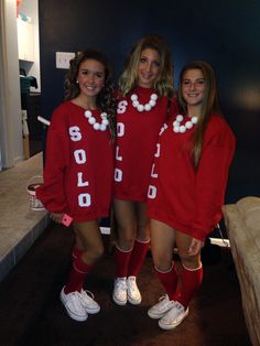 three girls in matching red sweaters posing for the camera with one girl wearing white tennis shoes