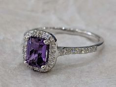 an engagement ring with a purple stone surrounded by diamonds