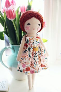 a doll is standing next to a vase with tulips