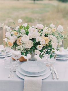 a table set with plates, silverware and flowers