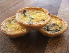 three small quiches sitting on top of a wooden table