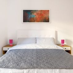 a bedroom with a bed, nightstands and painting on the wall