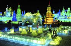 an ice castle lit up at night with people standing around it and lights on the ground