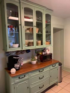 a kitchen with green cabinets and white tile flooring