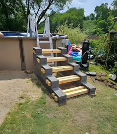 an above ground swimming pool with steps made out of wood and sand in the foreground