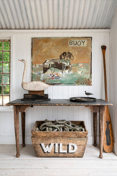 an old wooden table with two buckets on it and a painting in the background