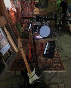 an electric guitar sitting on top of a rug next to a musical keyboard and amp