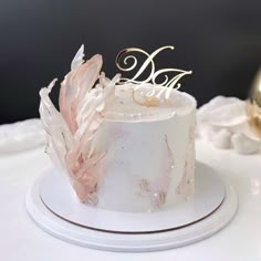 a white cake with pink flowers and gold lettering on top is sitting on a table