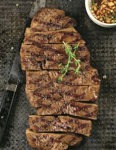 some meat is laying on a table next to a bowl and knife