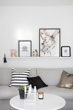 a white living room with black and white decor on the wall, coffee table and couch