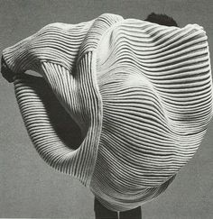 a black and white photo of a man standing in front of a sculpture