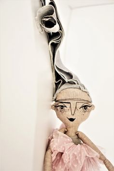 a cloth doll is hanging on the wall next to a metal object that looks like a woman's head