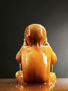 an orange sculpture sitting on top of a wooden table next to a black wall and floor