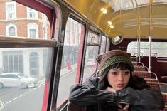 a woman sitting on a bus with her hand on her shoulder and looking out the window