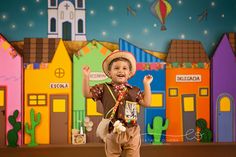 a young boy wearing a sombrero and standing in front of a colorful backdrop