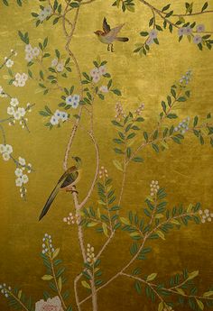 two birds sitting on a tree branch in front of a gold background with white flowers