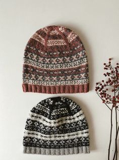 two hats sitting next to each other on top of a white surface with flowers in the background