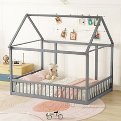 a child's bed with a teddy bear sitting in the bottom half, and a pink rug on the floor