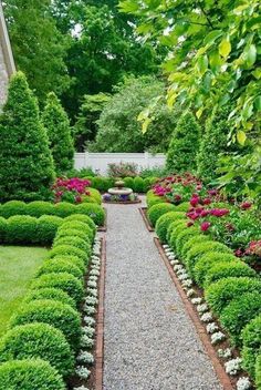 a garden with lots of green plants and flowers in the center, surrounded by gravel path