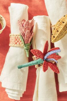 three napkins with embroidered flowers on them are sitting next to each other in front of folded towels