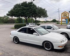 two white cars parked next to each other in a parking lot