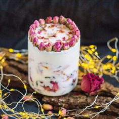 a jar filled with pink flowers sitting on top of a wooden table next to some branches