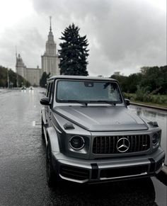 a mercedes g - class is parked on the side of the road in the rain