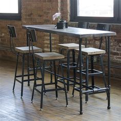 a table with four stools in front of a brick wall