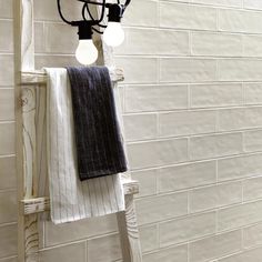 a towel hanging on a rack in front of a white brick wall with light bulbs