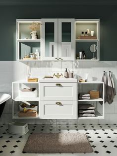 a bathroom with black and white tile flooring, cabinets and rug on the floor