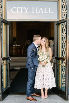 a man and woman standing in front of a city hall entrance