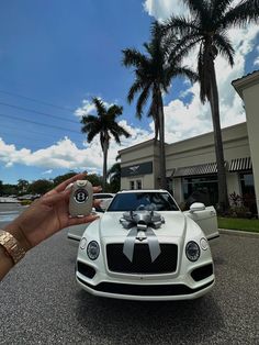 a person holding up a white car with a bow on it