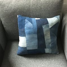 a blue and white pillow sitting on top of a gray couch