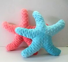 two blue and pink starfishs sitting next to each other on a white surface