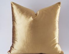 a gold pillow on a white background with no one in the photo to describe it