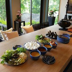 a wooden table topped with plates of food and bowls of sauces on top of it