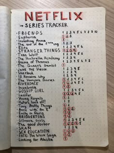 a notebook with a list of netflix's in it on top of a wooden table